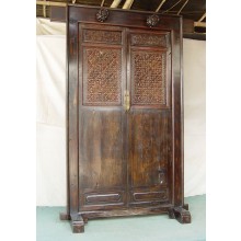 Die Vollholztür aus China ist in dunklem Holz gehalten und mit Schnitzereien verziert